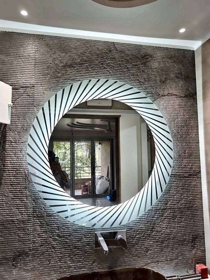 Round sunburst LED mirror glowing on a stone-finish bathroom wall